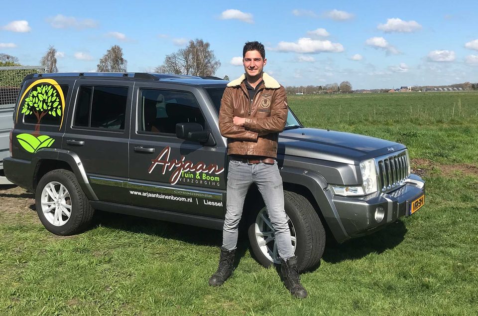 Hovenier Arjaan van Schelven bij zijn bedrijfsauto in de weilanden bij Liessel