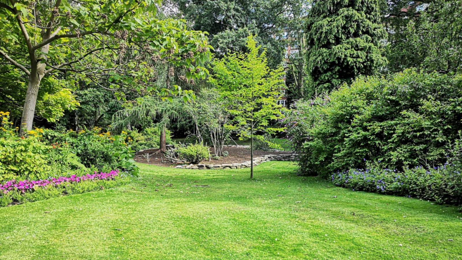Verzorgde tuin met gazon, bloeiende borders en bomen